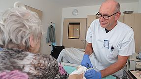 Carer looks after patient in hospital room.