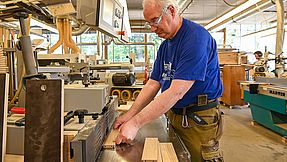Employee sawing wood in a workshop.