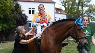 Man sits on a therapy horse and laughs