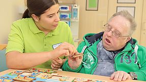 Employee assists patients with a wooden puzzle.