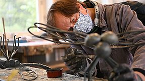 Man working on a steel figure in a workshop.