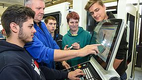 Instructor explains something to apprentices on the computer.