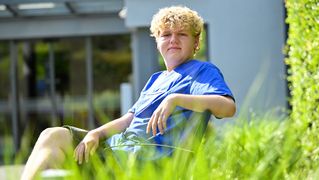 Jonah Lochmüller sitzt auf einer Bank im Garten von Haus Hawila.