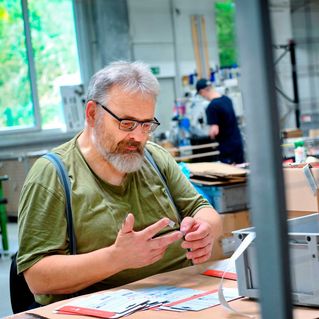 Wolfgang Starck sitzt an seinem Arbeitsplatz und klebt Etiketten