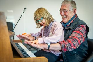 Wolfgang Spode und eine Schülerin spielen gemeinsam Klavier.