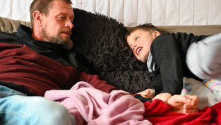 Father and son lie on the sofa.