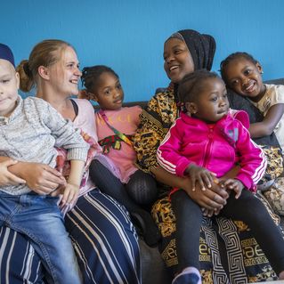 Zwei Frauen und ihre Kinder lachen gemeinsam.