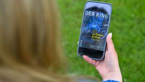 Eine Person hält ein Smartphone mit der digitalen Ausgabe von DER RING in der Hand.