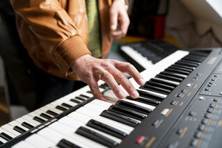 Eine Hand die ein elektrisches Keyboard spielt.