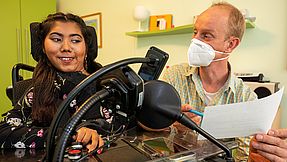 Employee does exercises with a girl in a wheelchair.