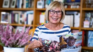 Klaudia Nußbaumer hält eine Zeitschrift in der Hand und lächelt in die Kamera.
