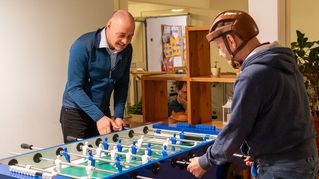 Pastor Dr. Bartolt Haase spielt am Kicker mit einem Klienten.