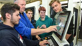 Instructor explains something to apprentices on the computer.