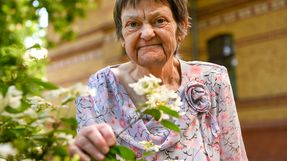 Eine Frau steht an einem Baum im Garten des Hospizes und hält einen blühenden Strauch in der Hand