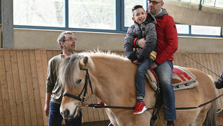 Marco Vohmann führt das Pferd mit Jonas und seinem Vater durch die Reithalle.