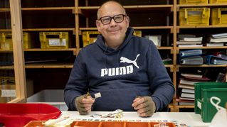Ein Mann sitzt an einemTisch und sortiert Briefmarken.