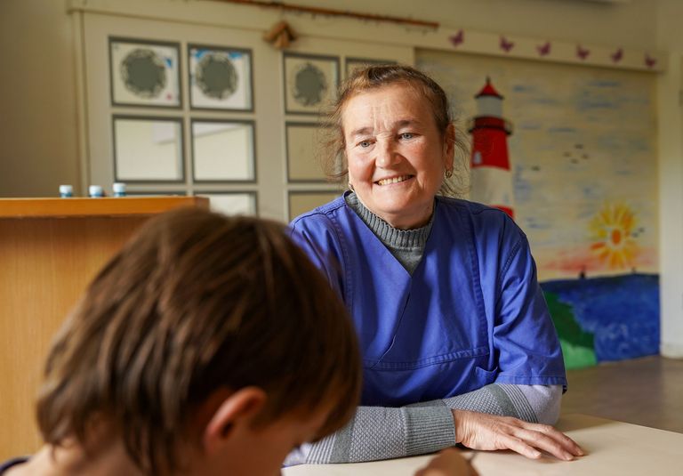 Olga Fastovez lächelt ein Kind an, das von hinten zu sehen ist