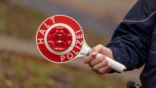 Polizist hat eine Polizeikelle in der Hand 