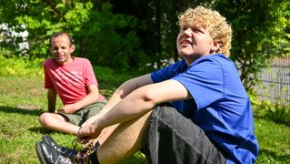 Jonah Lochmüller und ein Klient sitzen auf einer Wiese.