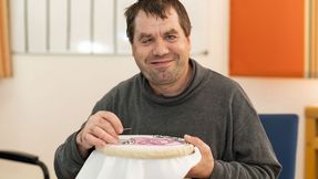 Ein Mann lächelt in die Kamera. In der Hand hält er Stick Werkzeug. 