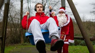 Nic Wollberg sitzt auf einer Schaukel, neben ihm steht der Nikolaus