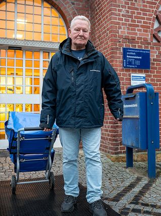 Andreas Zylla steht mit seinem Rollwagen vorm Eingang der Botenmeisterei.