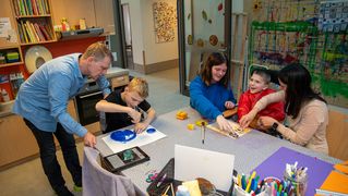 Familie Becker und eine Mitarbeiterin des Kinder- und Jugendhospizes verbringen Zeit in der Kreativwerkstatt. 