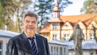 Martin Wulff steht vor der Statue des "Einladenden Christus" in Lobetal