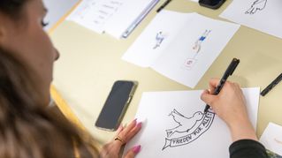 Frau malt Friedenstaube auf ein Papier