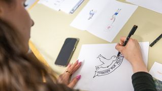 Eine Frau malt eine Taube auf Papier