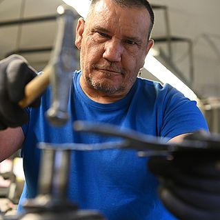 Heinz Eis bearbeitet Stahl mit dem Hammer. 