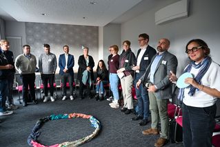 Die Teilnehmenden stehen in einem Kreis und tauschen sich aus