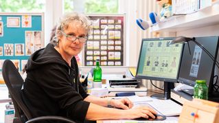 Ein Mann sitzt an seinem Schreibtisch und arbeitet am PC.