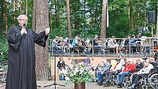 Pastor Pohl in der Waldkirche Lobetal vor Publikum