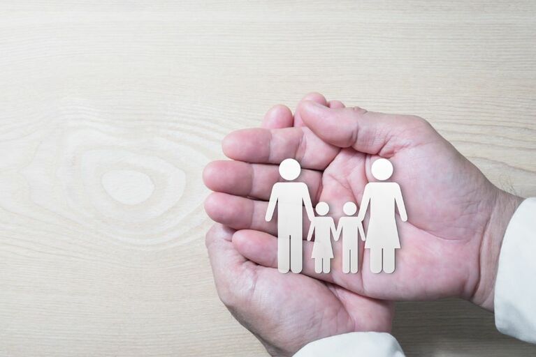 Zwei Hände die Figuren in der Hand halten. Die Figuren sind ein Mann, eine Frau, ein Junge und ein Mädchen.