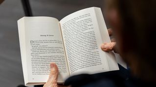 Eine Frau hält ein aufgeschlagenes Buch.