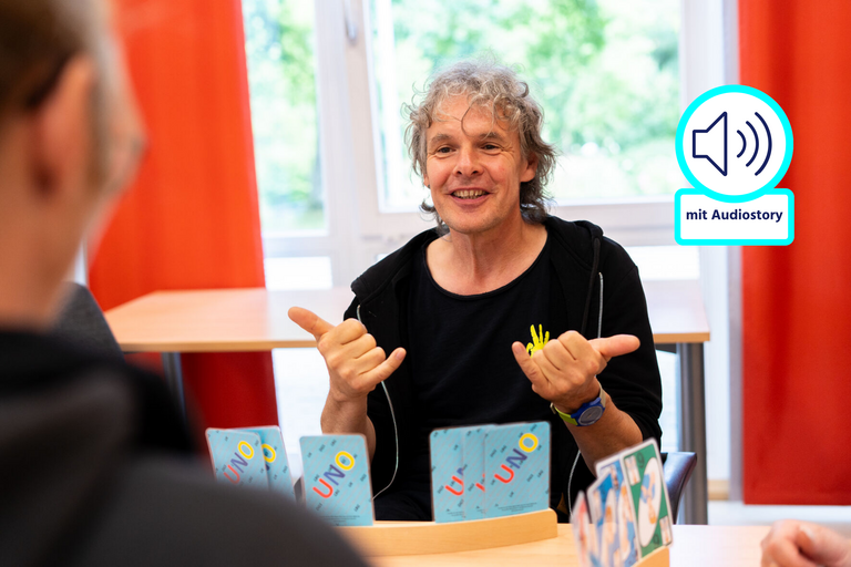 Ein sitzt einer anderen Person gegenüber und macht mit den Händen Gebärden.