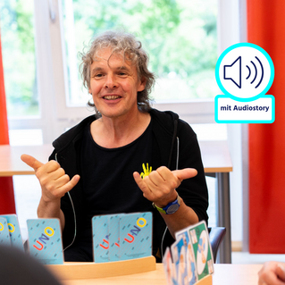 Ein sitzt einer anderen Person gegenüber und macht mit den Händen Gebärden. 