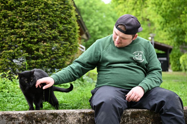 Ein junger Mann streichelt eine Katze.