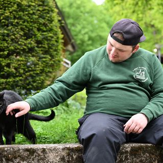 Ein junger Mann streichelt eine Katze.