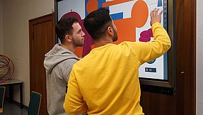 Zwei Schüler lernen am einem Touchscreen-Monitor.