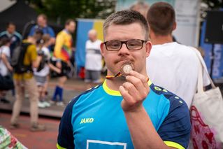 Ein Mann hält stolz seine Medaille in die Kamera.