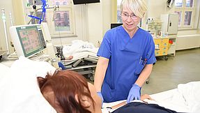 Carer looks after patient at hospital bed. 