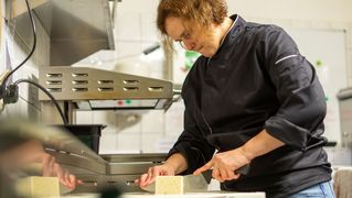 Sonja Schüler slices feta cheese in the kitchen.