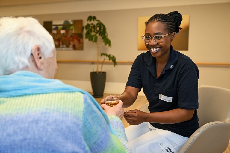 Eine Auszubildende hält die Hand einer Seniorin die Hände