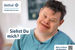 Plakatmotiv: Ein Mann schaut in die Kamera und lächelt.