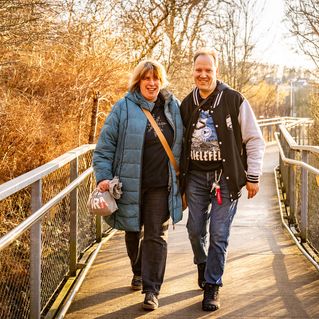 Carsten Linn und Julia Dreyer gehen auf einer Brücke durch die Natur