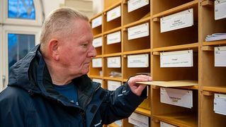 Andreas Zylla reaches into a mailbox.