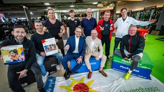 Gruppenbild im Fitnessstudio mit dem Leiter des Kinderhospizes mit Werbematerialien der Einrichtung. 