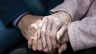 Zwei alte Menschen halten sich an den Händen